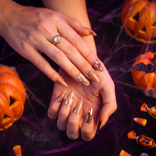 Woman wearing nude and gold Cancer II press-on nails with a Halloween-inspired look.